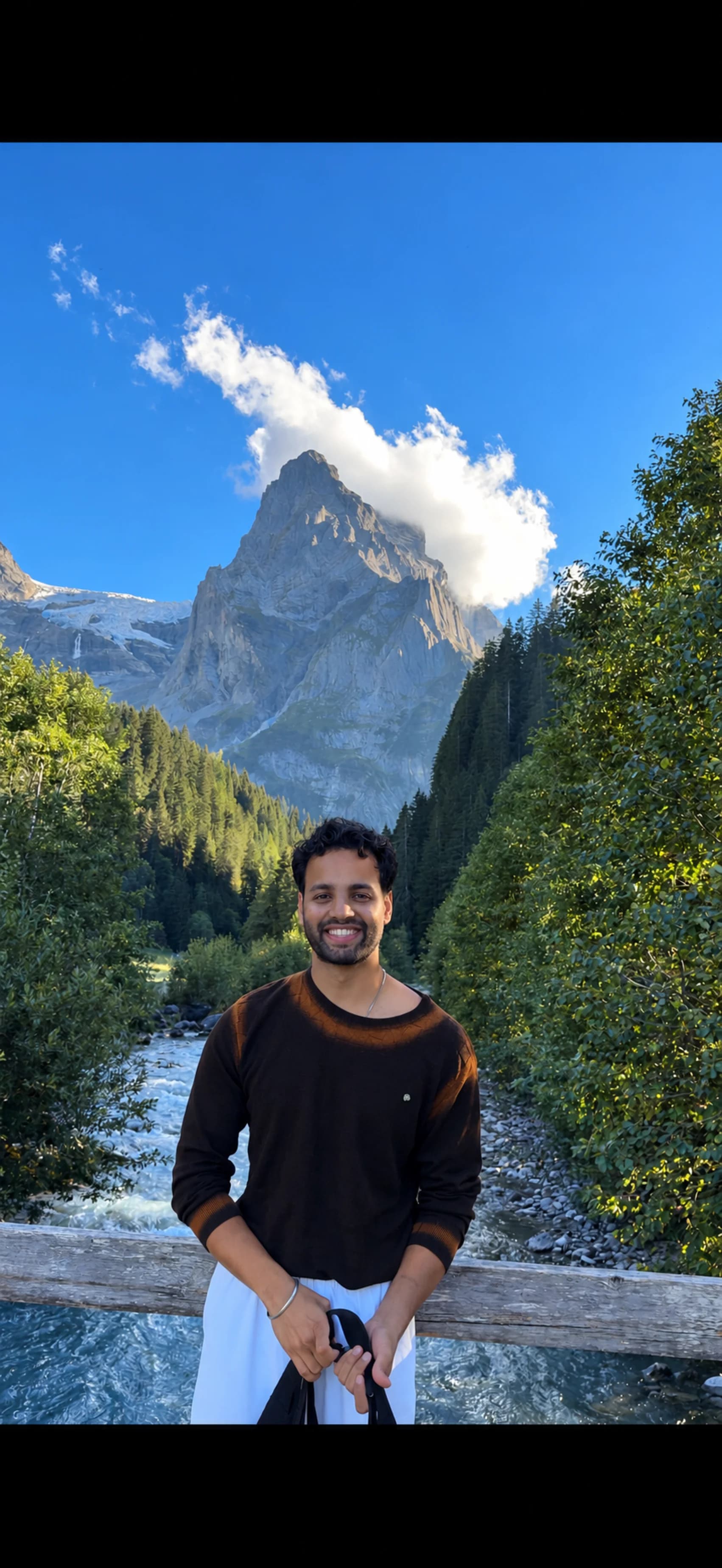 Sarthak Sharma smiling beside a stream in the Swiss Alps